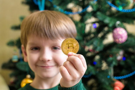 One Bitcoin in the hand of young boy. Concept. Crypto digital gold.