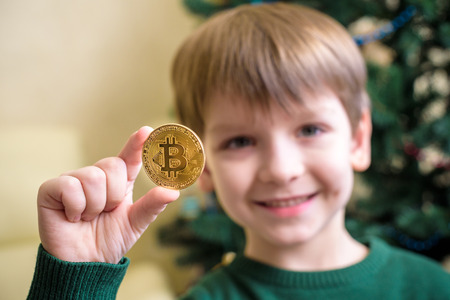One Bitcoin in the hand of young boy. Concept. Crypto digital gold.の写真素材