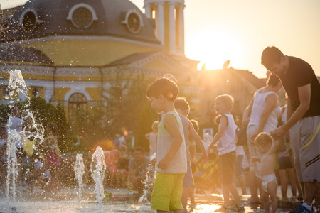 KYIV, UKRAINE AUGUST 13, 2017: Happy kids have fun playing in city water fountain on hot summer day. Parents with their children. Active family leisure, ecology concept.のeditorial素材