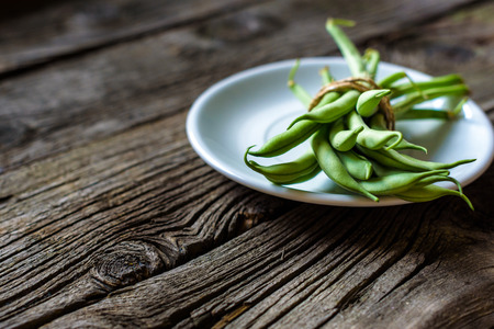 green string beans in a bowl on rustic wooden table.の写真素材