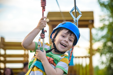 Young boy playing and having fun doing activities outdoors. Happiness and happy childhood concept. Boy swing on rope.の写真素材