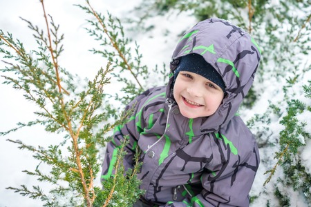 Winter portrait of kid boy in colorful clothes, outdoors during snowfall. Active outdoors leisure with children in winter on cold snowy days. Happy child having fun with snowの写真素材