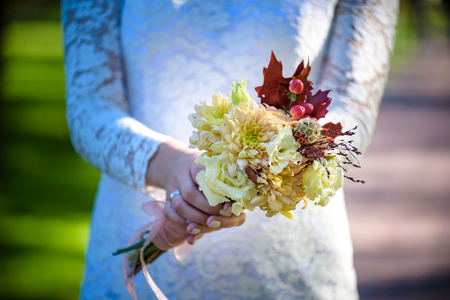 Bride holding colorful elegant modern autumn wedding bouquet in red, marsala, burgundy for a fall wedding.の写真素材