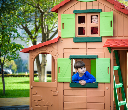 Two little boys playing together and having fun. Lifestyle family moment of siblings on playground. Kids friends play on tree house climbing on rope or stairs.の写真素材