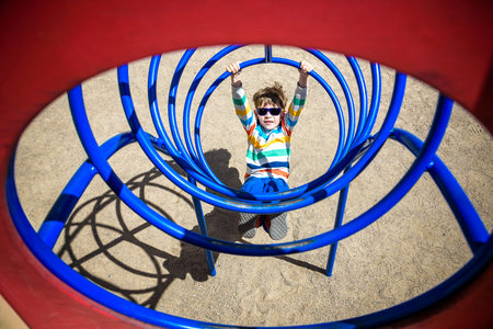 Cute young child boy or kid playing in tunnel on playground. Kid has a lot of fun.の写真素材