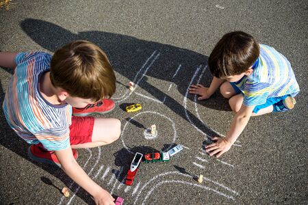 Two brothers sibling kid boy having fun with picture drawing traffic car with chalks. Creative...