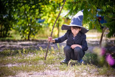 boy in pointed hat playing with magic wand outdoors. Little wizard. Halloween concept.の写真素材