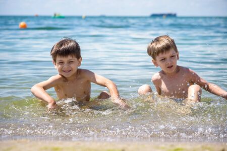 Happy family playing in blue water of swimming pool on a tropical resort at the sea. Summer vacations concept. Two brother kids are best friends.の写真素材