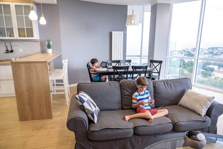One smart preteen schoolboy doing his homework with digital tablet at home. Child using gadgets on...