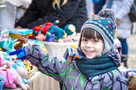 Little cute kid boy selecting decoration on Christmas market. Beautiful child shopping for toys and decorative ornaments. Traditional winter holiday event.の写真素材