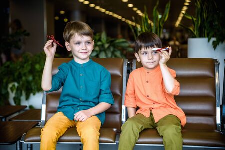 Two young brother boy dreaming of becoming a pilot. A child with a toy airplane plays at airport...