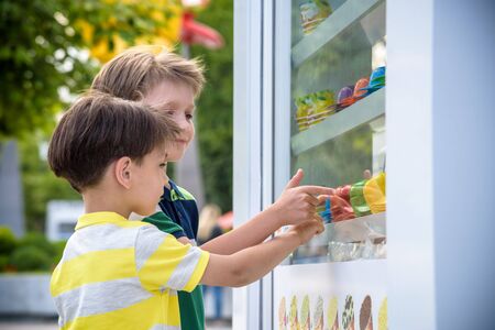 Portrait of cute adorable white Caucasian funny child boy looking at ice cream in shop window, trying to choose one, looking surprised puzzled, emotional face expression.の写真素材