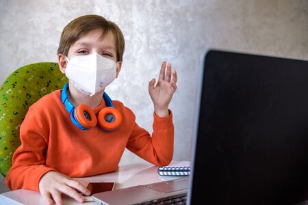 Coronavirus Outbreak. Lockdown and school closures. School boy with face mask watching online...