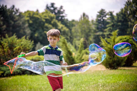Little boy playing with his soap bubbles toy in the park. Child activity. Springtime concept.