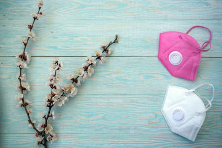 blooming cherry branch with disinfection liquid on wooden table. The flowers are covered with a blue...