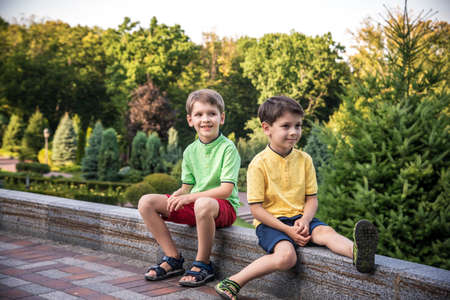 Two brother boy happy children playing outdoors. Kids having fun in park during summer vacation. Friends sit and smiling. Summer holiday concept.の写真素材