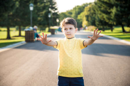 Happy child making a stop sign with his hand while standing at the road.の写真素材