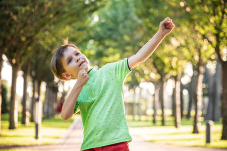Awesome young happy boy portrait. The cute little kid is in the park posing wearing casual clothes.