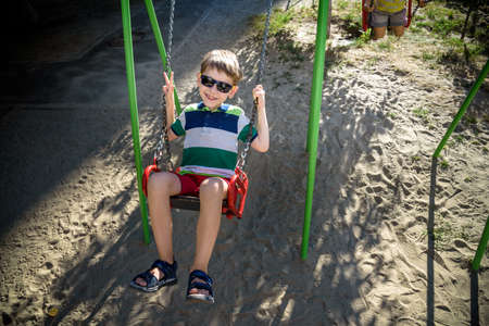 European boy on chain swing. Summer leisure time concept.