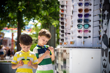 A child and a choice of sunglasses. Two little boys are standing in sun-proof glasses against the...