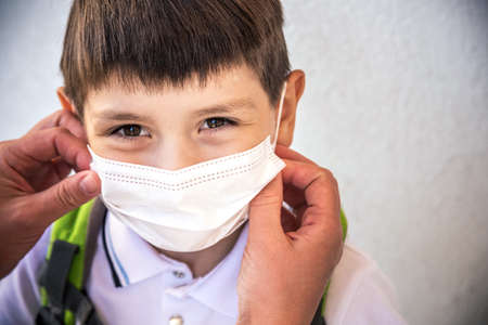 Closeup Kid face wearing protective face mask for pollution or virus, Cropped shot of school boy wearing protection mask against pm 2.5 air pollutionの写真素材