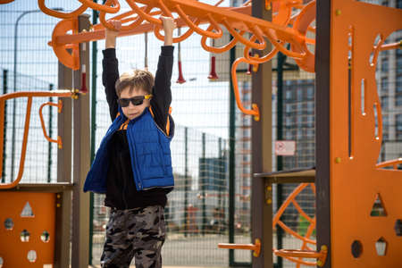 Cute boy is climbing on the playground in the schoolyard. He has a very happy face and enjoy this...