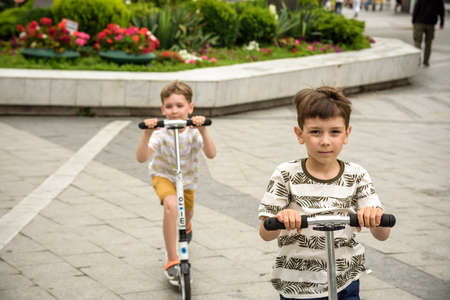 Odessa, Ukraine - July 05, 2021: Two Boy happy on a scooter in a city park.のeditorial素材