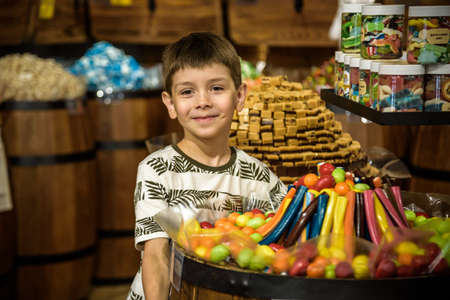 Odessa, Ukraine - July 05, 2021: Little cute kid boy near sweet stand with candy canes. Happy child with his sibling brother. Children s dreams concept.のeditorial素材