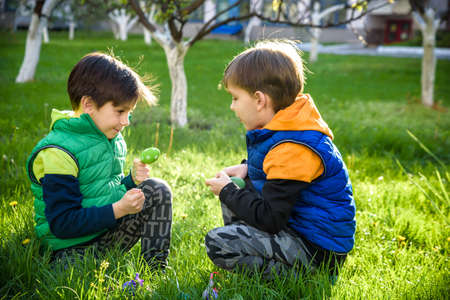 Kids on Easter egg hunt in blooming spring garden. Children searching for colorful eggs in flower...