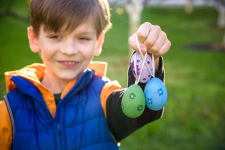 Different color Easter Eggs in a child's hands- egg hunt. Festive family traditional play game on...