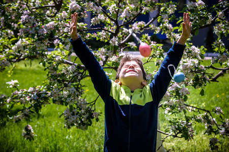 Boy throwing up color Easter Eggs after egg hunt. Traditional Easter concept. Happy boy smiling on...