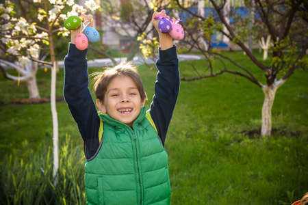 Different color Easter Eggs in a child's hands- egg hunt. Festive family traditional play game on Easter.の写真素材