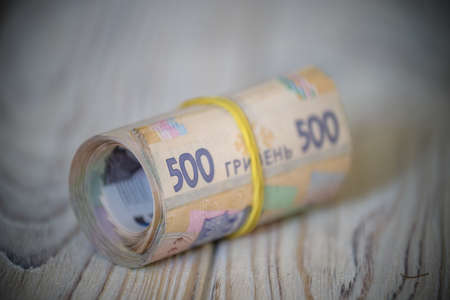 new Ukrainian hryvnia. 500 hryvnia on wooden table bind with rubber tape to tube. money background and wealth concept.の写真素材