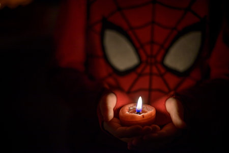 Boy alone on Halloween with candle in dark room. Selective focus. Low light scene with artistic color noise.の写真素材