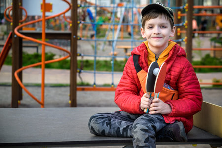 Happy ping pong player think about a game. young boy sitting after match on a tennis table outdoors.の写真素材
