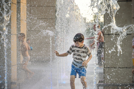 Boy having fun in water fountains. Child playing with a city fountain on hot summer day. Happy kids having fun in fountain. Summer weather. Active leisure, lifestyle and vacation.の写真素材