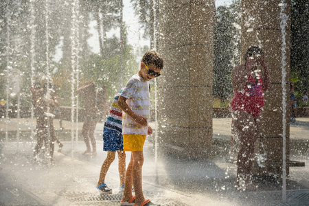 Boy having fun in water fountains. Child playing with a city fountain on hot summer day. Happy kids having fun in fountain. Summer weather. Active leisure, lifestyle and vacation.の写真素材