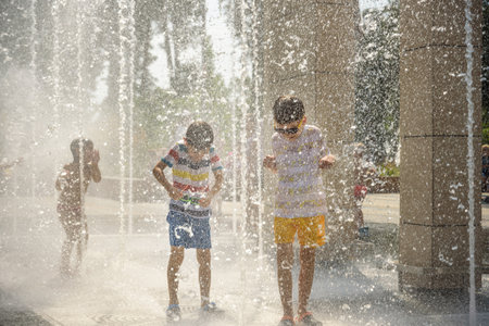 Boy having fun in water fountains. Child playing with a city fountain on hot summer day. Happy kids having fun in fountain. Summer weather. Active leisure, lifestyle and vacation.の写真素材