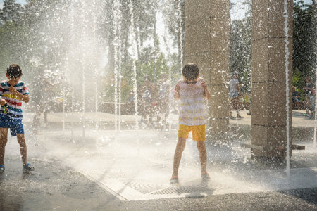 Boy having fun in water fountains. Child playing with a city fountain on hot summer day. Happy kids having fun in fountain. Summer weather. Active leisure, lifestyle and vacation.の写真素材