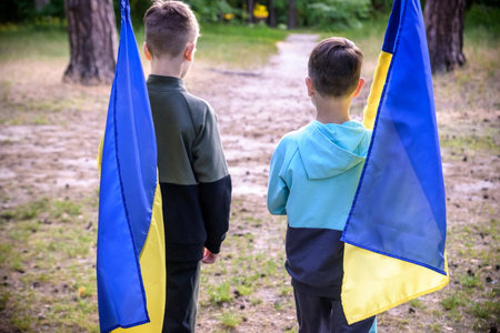flags of Ukraine in hands of two boys. Children hold Ukrainian flags yellow and blue waving in wind . Ukraine's Independence Day. Flag Day.の写真素材