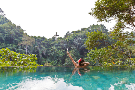 girl in the tropic jungle pool with a glass of champagneの写真素材
