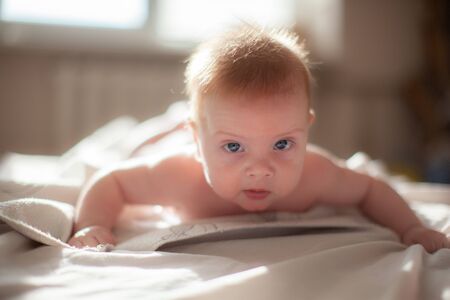 infant laying on the bed in the lights of sunの写真素材