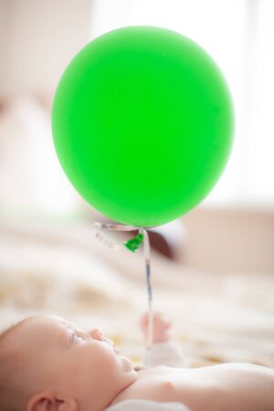 infant with green baloon layingの写真素材
