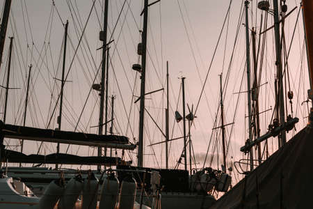 The tops of sailing boat masts against a sunset with no clouds during the winter.の写真素材