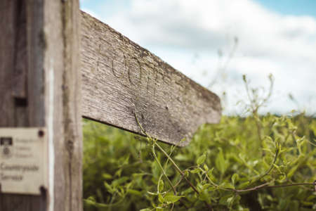 Footpath sign with green background. wooden footpath sign. Wooden footpath sign in the country side leading on to a gravel footpath.の写真素材