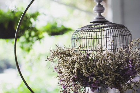 White birdcage used as a decorative vase with flowers.