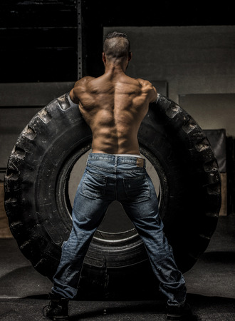 Muscles with large tire showing a very muscular back and blue jeansの写真素材