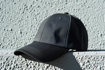 Black baseball cap on a white wall. Close-up of cap.の素材