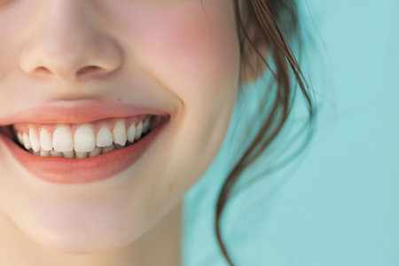 Close up of a beautiful young woman's teeth on blue background.の素材