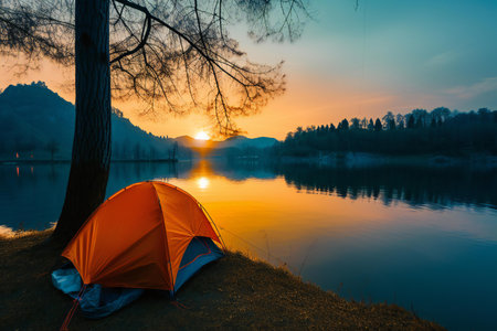Camping tent on the lake at sunset or sunrise with reflection in waterの素材